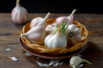 Garlic is a ripe, spicy product, a spice. It is essential in the preparation of many delicious dishes. On an old background in a composition with kitchen accessories.