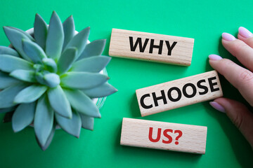 Why choose us symbol. Concept words Why choose us on wooden blocks. Beautiful green background with succulent plant. Businessman hand. Business and Why choose us concept. Copy space.
