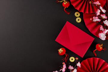 Special presents to honor the spirit of Chinese New Year. Top view photo of red featuring fans, envelope, sakura bloom, lucky coins on black background with promo zone