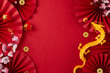 Theme for Chinese New Year: honoring traditions. Top view flat lay of gold dragon, red paper fans, traditional coins, sakura bloom on red background with advert area - obrazy, fototapety, plakaty