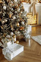 Christmas gifts under the Christmas tree at home. Beige and gold shades.