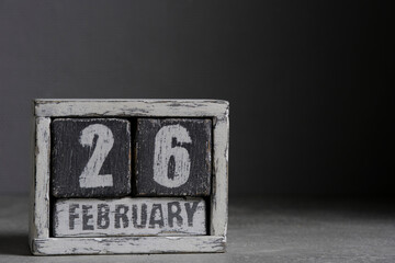 February 26 on wooden calendar, on dark gray background.