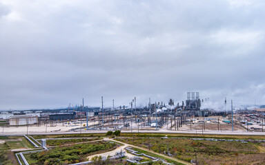 Aerial view of a Fuel Refinery in Port Arthur Texas, located on the Gulf Coast,  with fuel storage, pipelines, steam rising from tall chimneys and an overcast sky above.