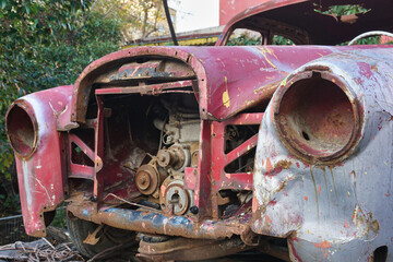 Front part of old and abandoned classic red car with exposed engine