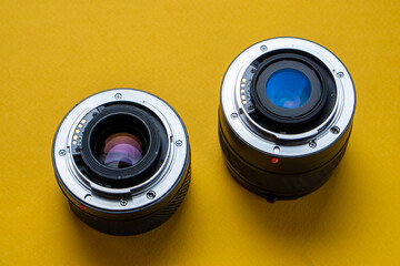 Camera lenses on a yellow background. Optical devices for image focusing. - obrazy, fototapety, plakaty