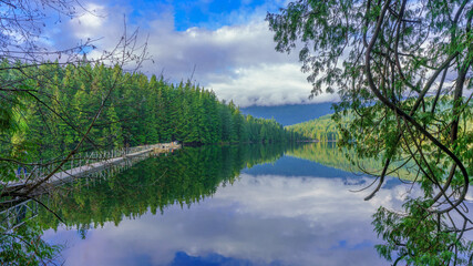 Float bridge on Sasamat Lake in Belcarra Provincial Park as viewed from Sasamat Loop forest trail on a bright winter day.