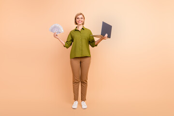 Full length photo of successful woman dressed green shirt hold laptop win money in online casino isolated on beige color background
