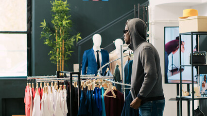 African american thief trying stole trendy clothes being caught by store security guard in clothing...