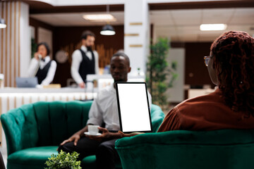 African american people at hotel using tablet with white screen, looking at blank template display...