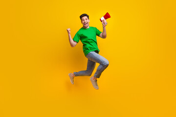 Fototapeta na wymiar Full length photo of satisfied ecstatic man jumping holding loudspeaker shout yeah win lottery isolated on yellow color background