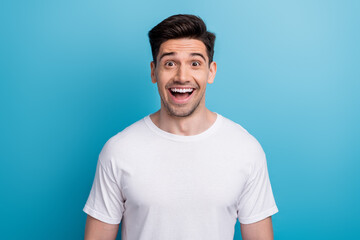 Obraz premium Photo of impressed funky man dressed white t-shirt smiling open mouth isolated blue color background