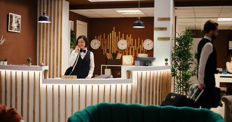 Happy professional hotel personnel doing various administrative tasks in stylish hotel reception....