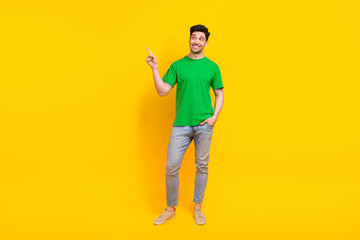 Fototapeta premium Full length photo of positive man dressed green t-shirt jeans look directing at sale empty space isolated on yellow color background