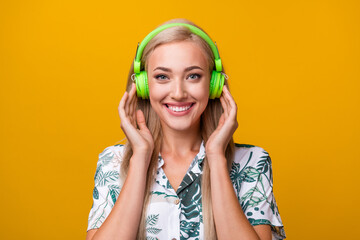 Photo of good mood gorgeous girl with long hairdo dressed print shirt arms touching headphones isolated on yellow color background