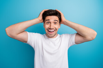 Photo of excited funny man dressed white t-shirt smiling arms head open mouth isolated blue color...