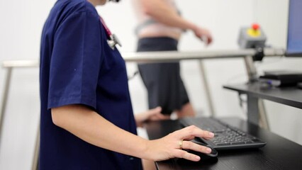 Video of a cardiologist monitoring the heart rate of a man walking on a treadmill during a cardiac stress test