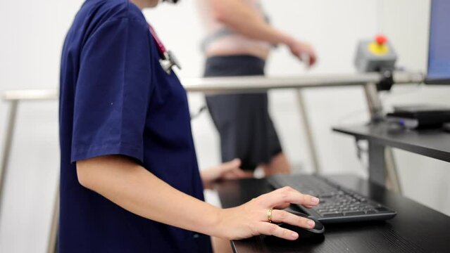 Video of a cardiologist monitoring the heart rate of a man walking on a treadmill during a cardiac stress test