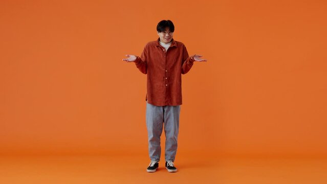 Confused asian man shrugging and feeling awkward in studio