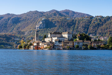 Fototapeta na wymiar San Giulio Island within Lake Orta in Piedmont, Italy. colorful mountains in autumn, blue water and buildings