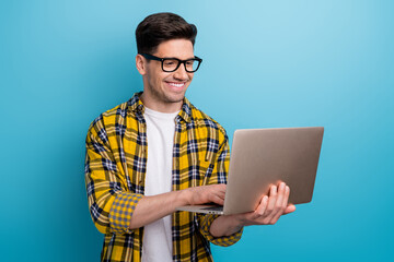 Photo of intelligent man with bristle dressed plaid yellow shirt in eyewear typing email on laptop...