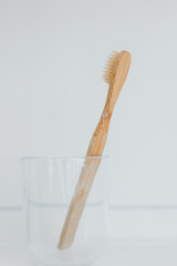 Teeth cleaning. bamboo Toothbrush in bathroom. toothbrush in a transparent glass cup on the sink in...