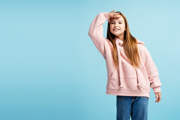 Positive beautiful girl looking away standing isolated on blue background, copy space