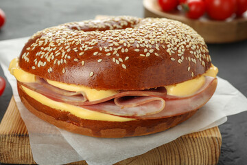 Delicious bagel with ham and cheese on grey table, closeup