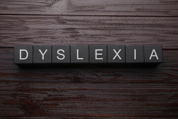 Black cubes with word Dyslexia on wooden background, flat lay