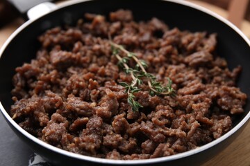 Fried ground meat and thyme in frying pan on table, closeup