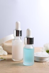 Bottles of cosmetic serum on wooden table