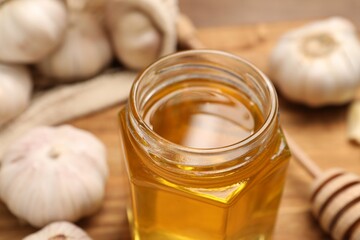 Jar with honey and garlic on table, closeup