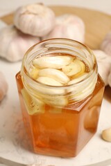 Honey with garlic in glass jar on board, closeup