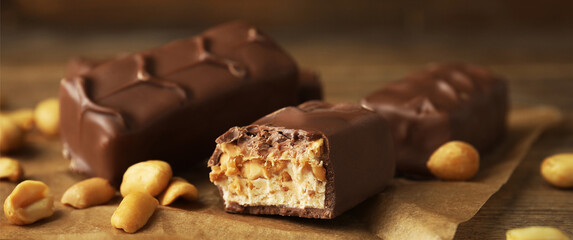 Chocolate candy bars with caramel, nuts and nougat on table, closeup. Banner design