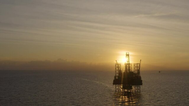 Aerial view of silhouette offshore jack up drilling rig during sunset - oil and gas industry
