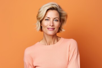 Portrait of a beautiful middle-aged woman with short blonde hair on orange background