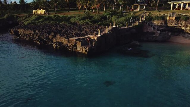 Drone shot of Taga beach with a girl diving from the cliff