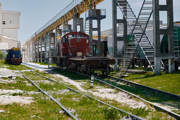 Small diesel locomotive on railway tracks in factory yard