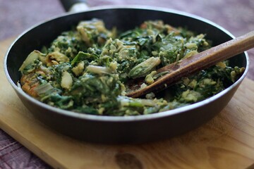 chard greens cooked in a frying pan, on a chopping board, on a chopping board