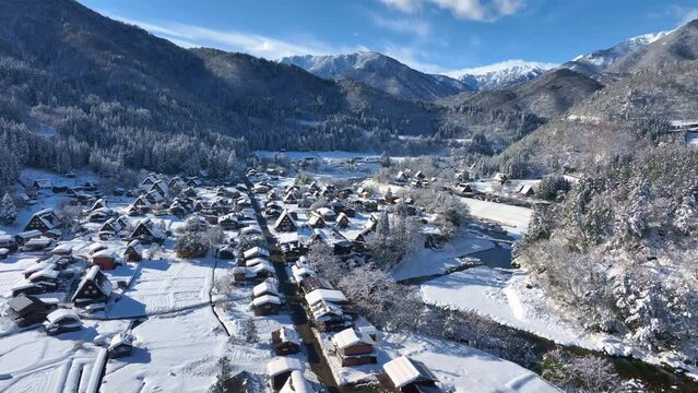 Winter holidays in snowy mountains in Japan, drone view of Shirakawago village in Japan in winter, snowy winter wonderland on a sunny frosty day in a mountain valley, Japanese winter tourism. 