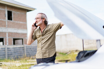 Stressed caucasian white old man using mobile phone calling to roadside assistant service for help...
