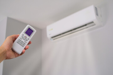 Man's hand using remote control open The air conditioner is cooled to 25 degrees Celsius in his bedroom. Health concepts and energy savings - obrazy, fototapety, plakaty