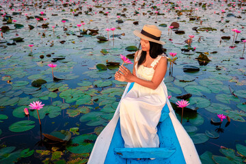 The sea of red lotus, Lake Nong Harn, Udon Thani, Thailand. Asian woman with hat and dress on a...