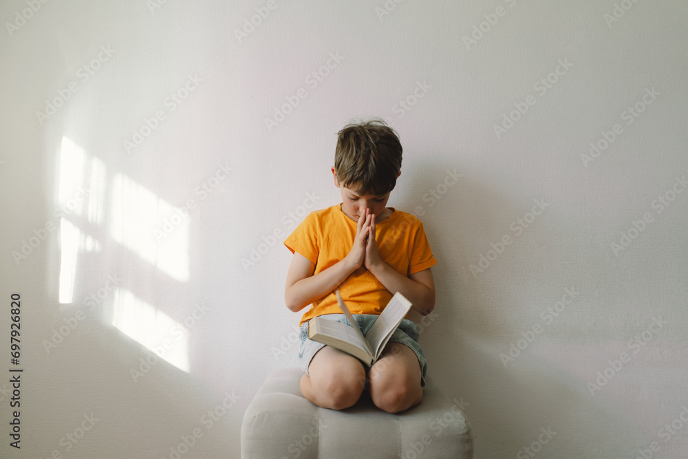 Wall mural christian boy holds bible in her hands. reading the holy bible. concept for faith, spirituality and 