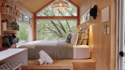 Cinematic slider going across timber tiny cabin with luxury furnishings and large floor to ceiling windows looking out to the national park. - Powered by Adobe