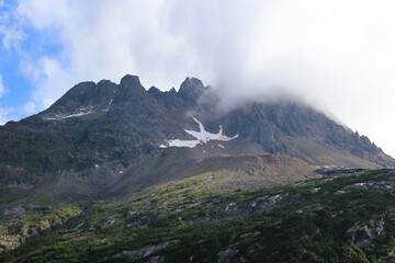 Clouds hanging over the top of rugged mountains in Southern Alaska