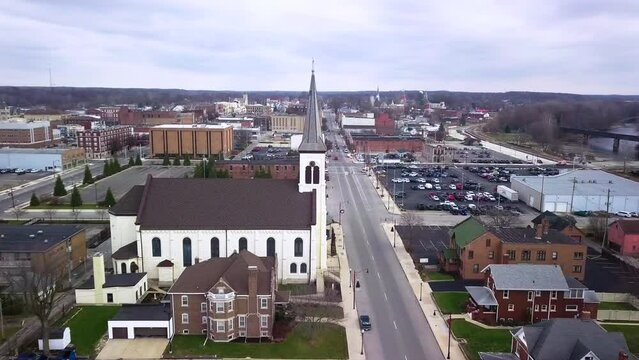 Aerial view flyover Logansport small white church with steeple in downtown Indiana townscape
