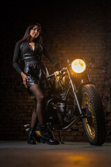 Fototapeta na wymiar Young beautiful girl with dark hair on the old motorbike. Girl motorbiker.