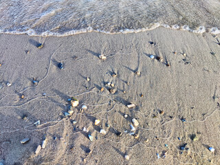 Yellow sand, pebbles and a transparent wave as a background, texture. Abstract pattern, place for text, copy space