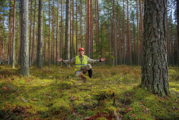 Forest engineer works in the forest. A man working, looking at the camera. The worker spread his...