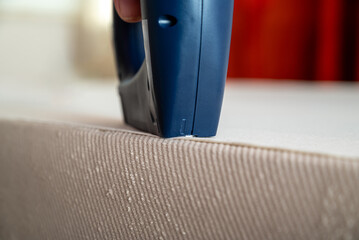 Worker stapling sofa lining with electric staple gun